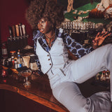 Woman sitting at a bar counter in a stylish outfit with a dark background