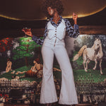 Person in a stylish outfit standing in front of a colorful mural with animals.