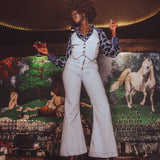 Person in a stylish outfit standing in front of a colorful mural with animals.