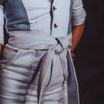 Light blue jumpsuit with a belt worn by a person, against a dark background