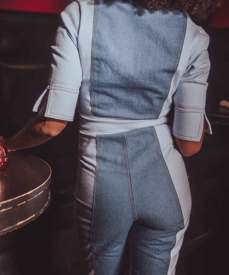 Person wearing a denim and white outfit in a dark setting