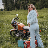 Woman in a light blue outfit standing next to a motorcycle in a grassy field Soul Sister since 1969..
