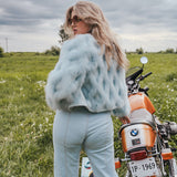 Woman in a field with a motorcycle, wearing a fur coat and sunglasses Soul Sister since 1969..