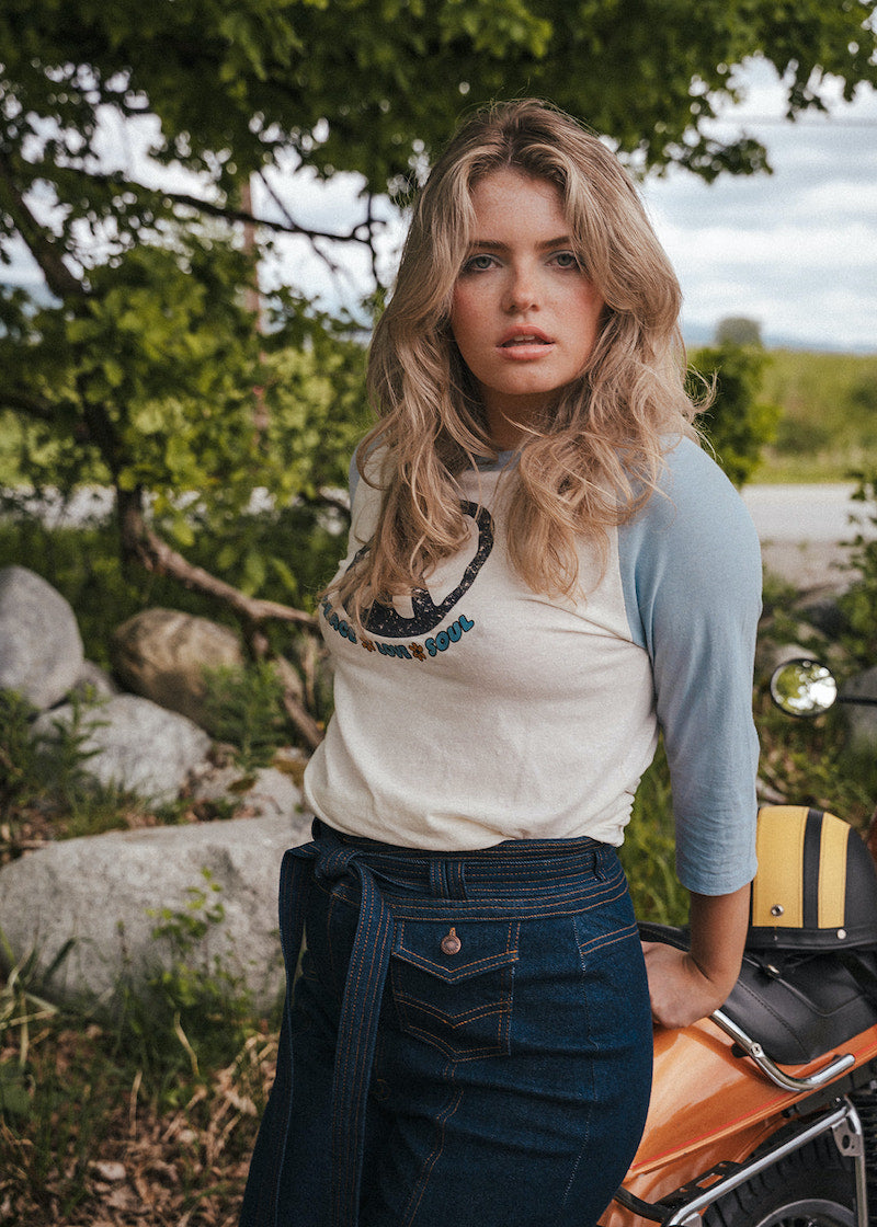 Woman standing outdoors with a scenic background Woman wearing a peace symbol shirt with text outdoors wearing Soul Sister since 1969