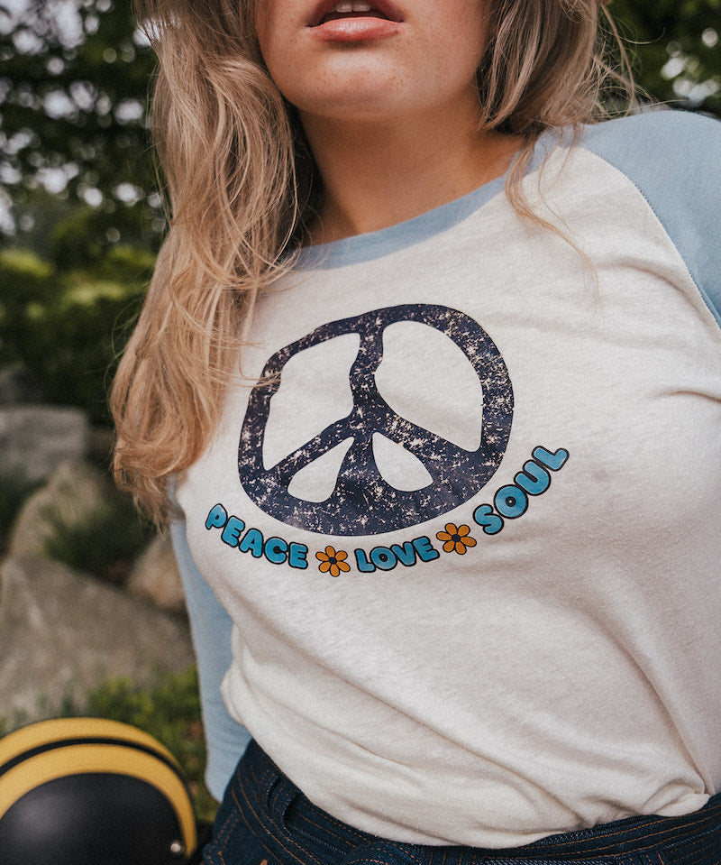 Person wearing a shirt with a peace symbol and text outdoorsWoman wearing a peace symbol shirt with text outdoors wearing Soul Sister since 1969
