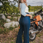 Woman standing next to a motorcycle in a natural setting Woman wearing a peace symbol shirt with text outdoors wearing Soul Sister since 1969