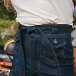 Person wearing a white t-shirt with a graphic design and blue jeans, standing next to a motorcycle wearing Soul Sister since 1969..