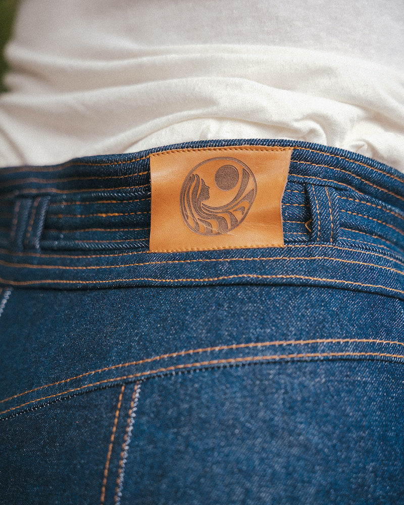 Close-up of blue jeans with a leather label featuring a circular design wearing Soul Sister since 1969..
