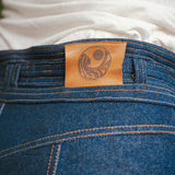 Close-up of blue jeans with a leather label featuring a circular design wearing Soul Sister since 1969..