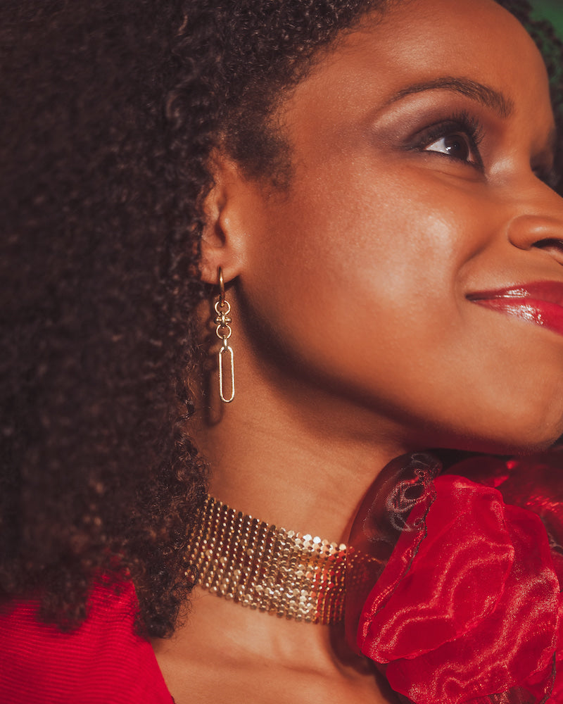 Close-up of a woman wearing gold jewelry with a red rose