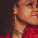 Close-up of a woman wearing gold jewelry with a red rose