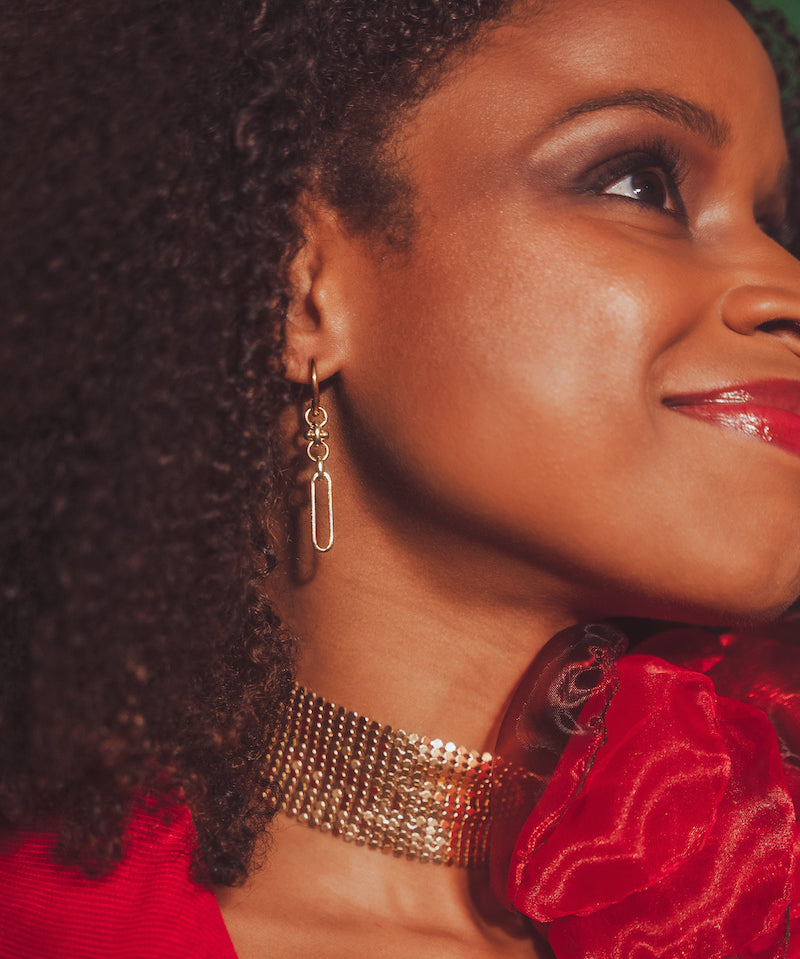 Close-up of a woman wearing gold jewelry with a red rose