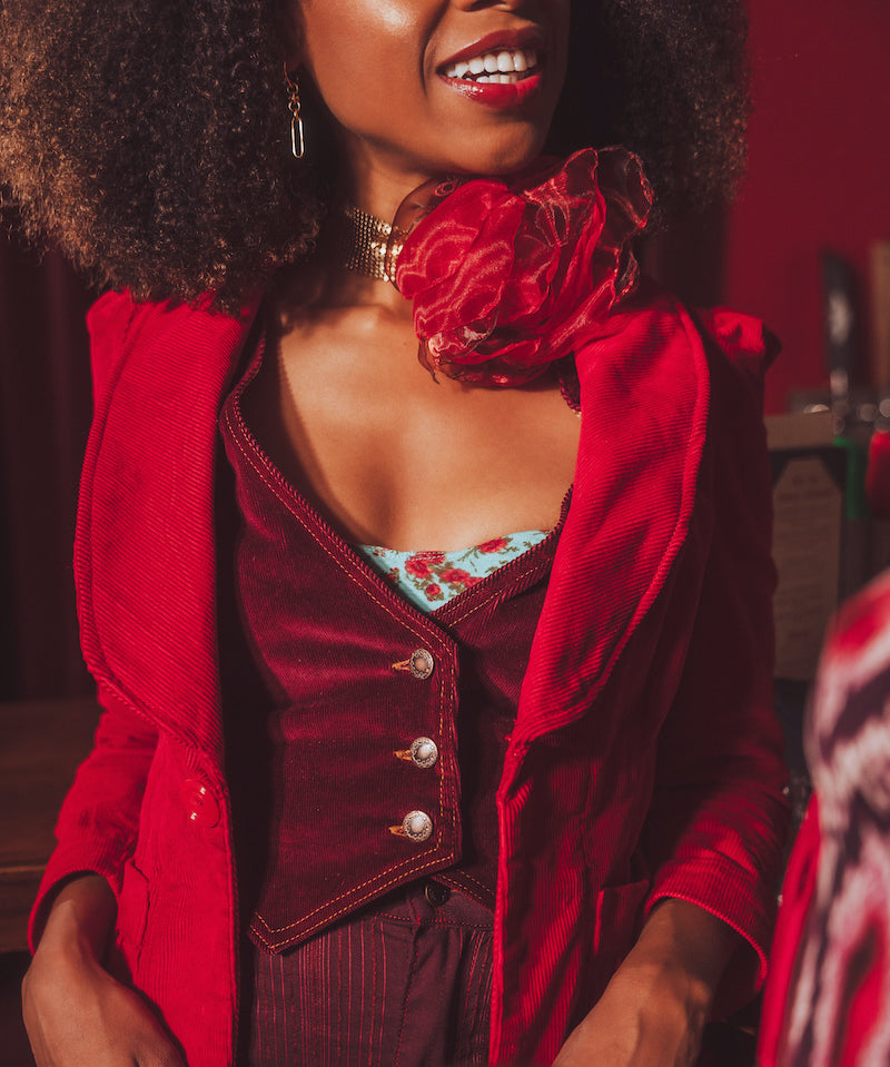 Woman wearing a red outfit with a floral top, sitting indoors.