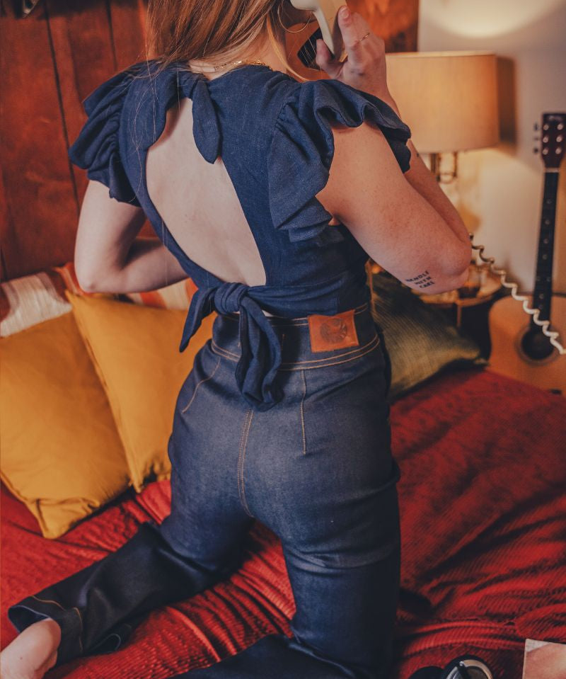 Person wearing a blue top with ruffled sleeves in a bedroom setting.