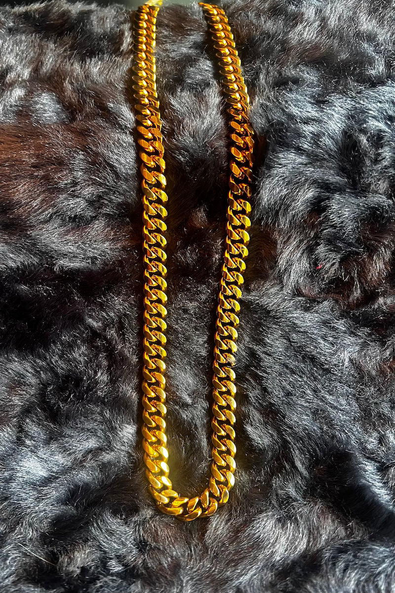 Gold chain necklace on a textured gray surface