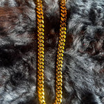 Gold chain necklace on a textured gray surface