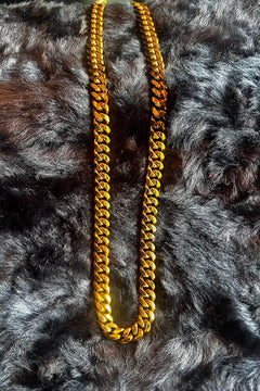 Gold chain necklace on a textured gray surface