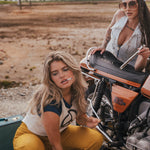 Two women with a motorcycle in an open field with mountains in the background wearing Soul Sister since 1969
