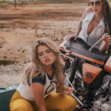Two women with a motorcycle in an open field with mountains in the background wearing Soul Sister since 1969