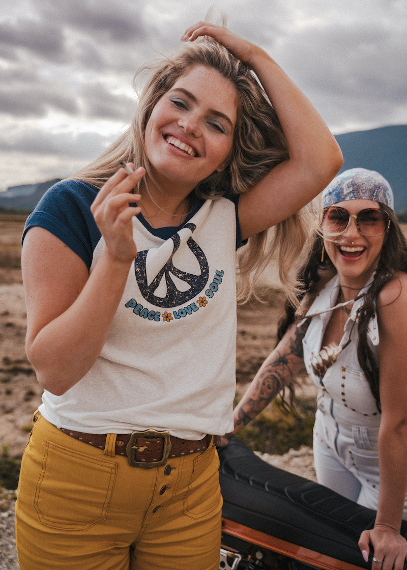 Two women standing outdoors with a scenic background wearing Soul Sister since 1969

