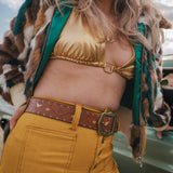 Person wearing a gold top and mustard pants with a patterned jacket wearing soul sister since 1969.