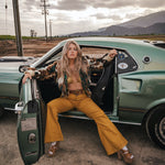 Woman sitting in a vintage car with a scenic background wearing soul sister since 1969