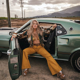Woman sitting in a vintage car with a scenic background wearing soul sister since 1969