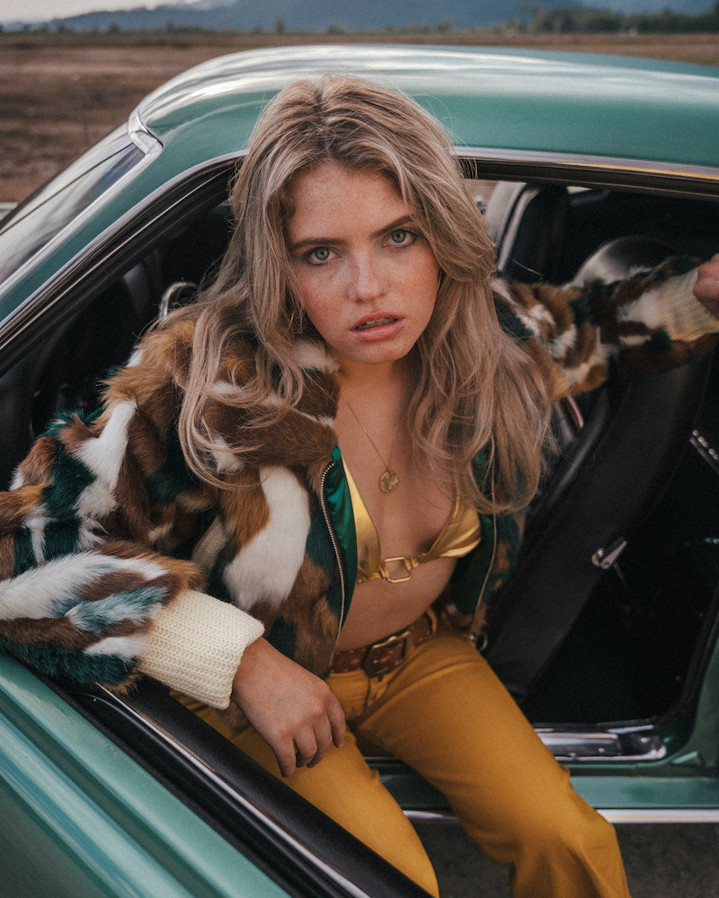Woman sitting in a vintage car with a scenic background wearing Soul Sister since 1969