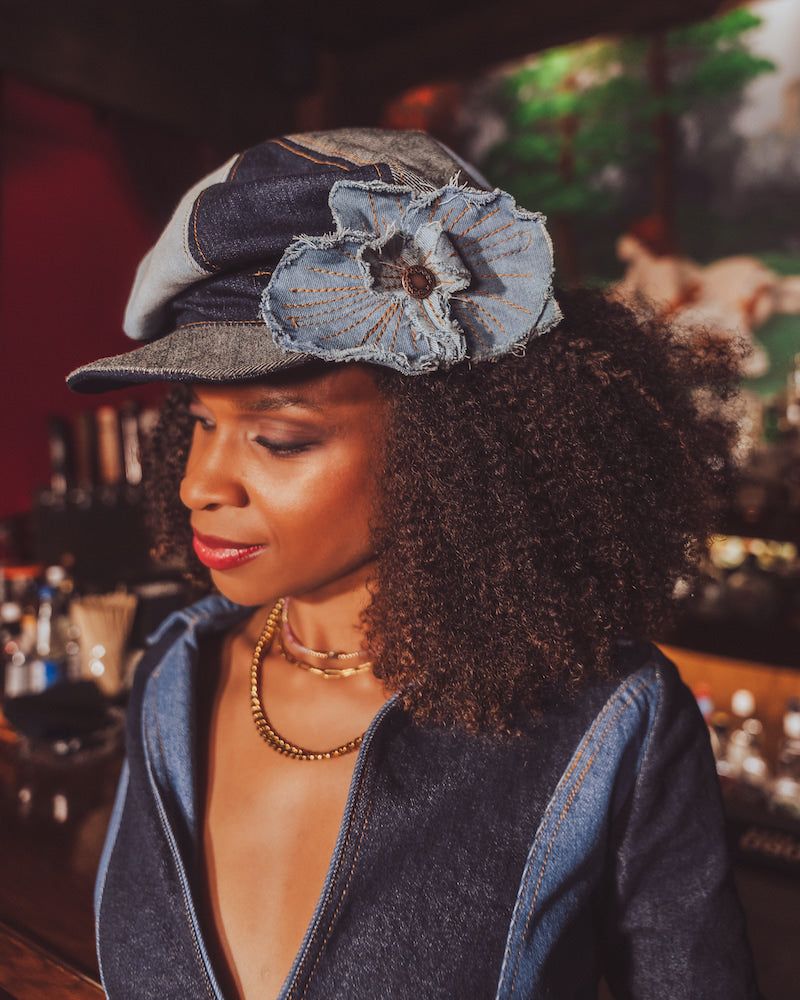 Woman wearing a denim cap with a flower accessory in a bar setting
