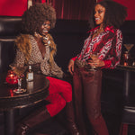 Two women sitting in a stylish bar setting with drinks and decor.