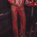Person wearing a red patterned shirt and red pants in a dimly lit room.