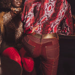 Person wearing a patterned red jacket and red pants with a dark background