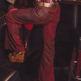 Person wearing a patterned shirt and red pants sitting inside a vehicle.