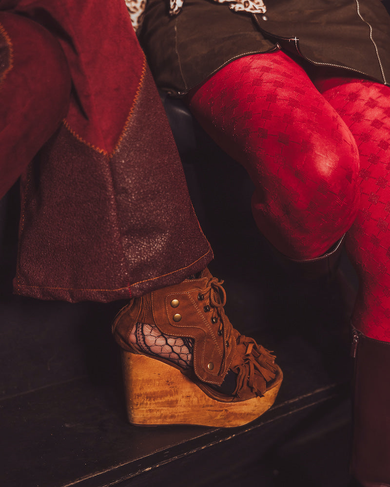 Brown wedge shoe with wooden sole worn by a person in red pants.