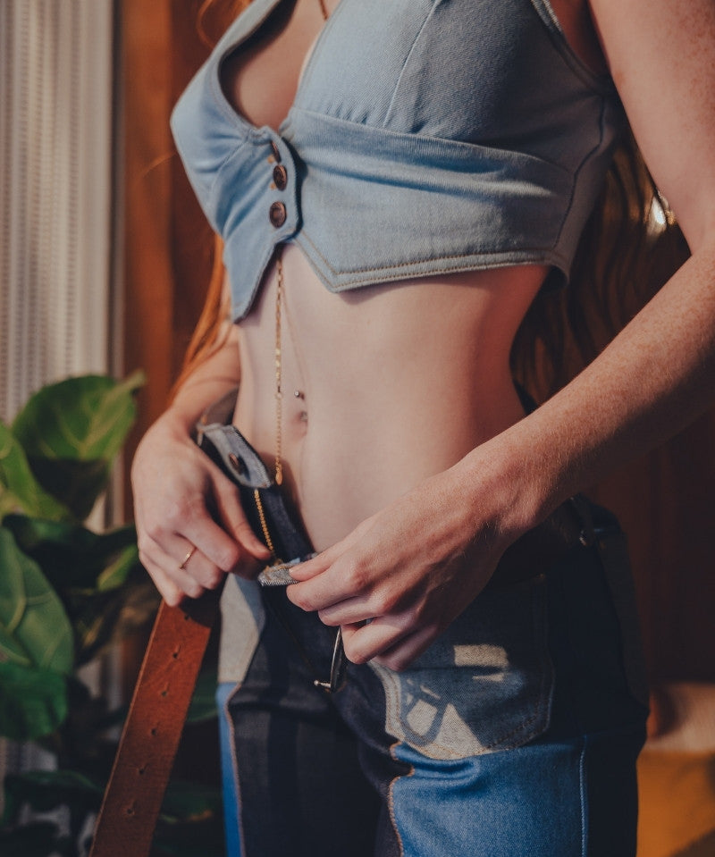 Person wearing a denim crop top and jeans with a blurred background