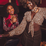 Two women in stylish outfits with leopard print and red accents in a dimly lit setting.