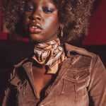 Woman wearing a brown jacket and gold scarf with a red background