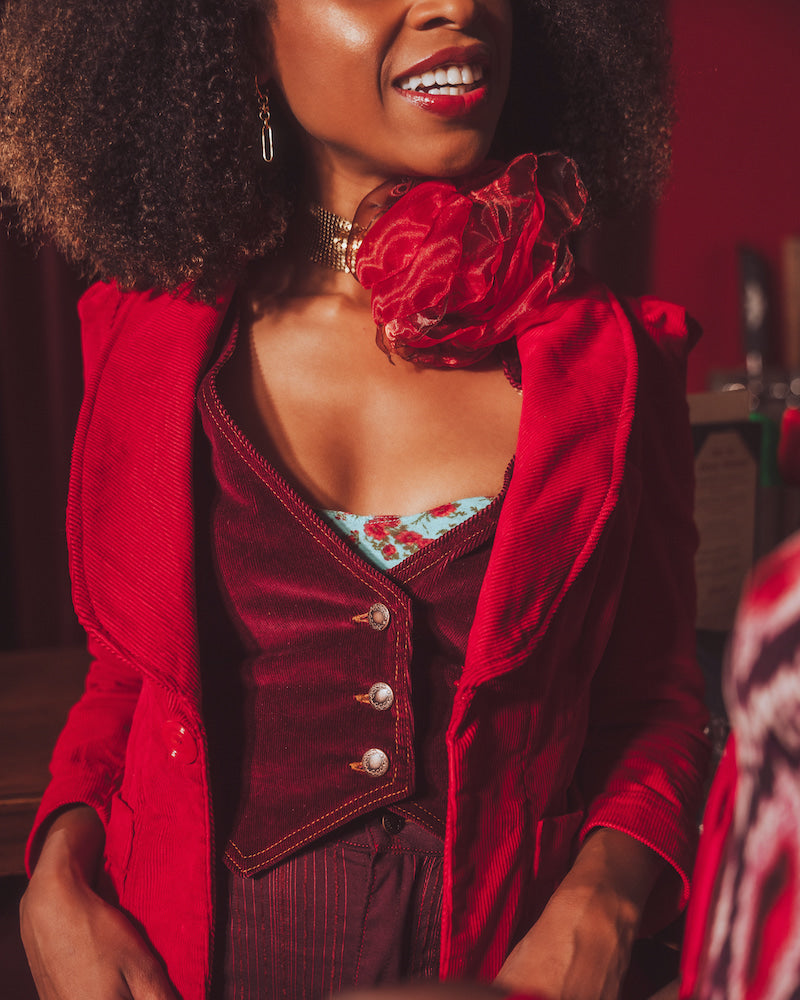 Woman wearing a red outfit with a floral top, sitting indoors.