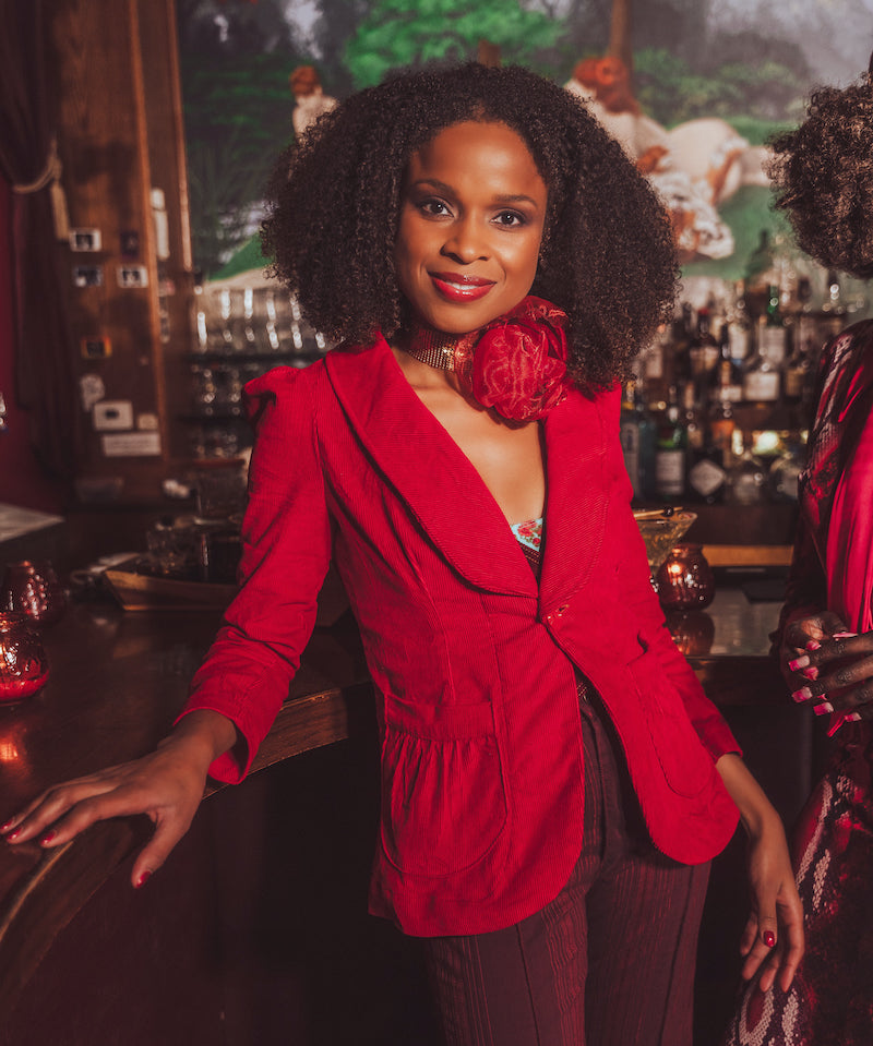 woman standing at a bar wearing red french blazer