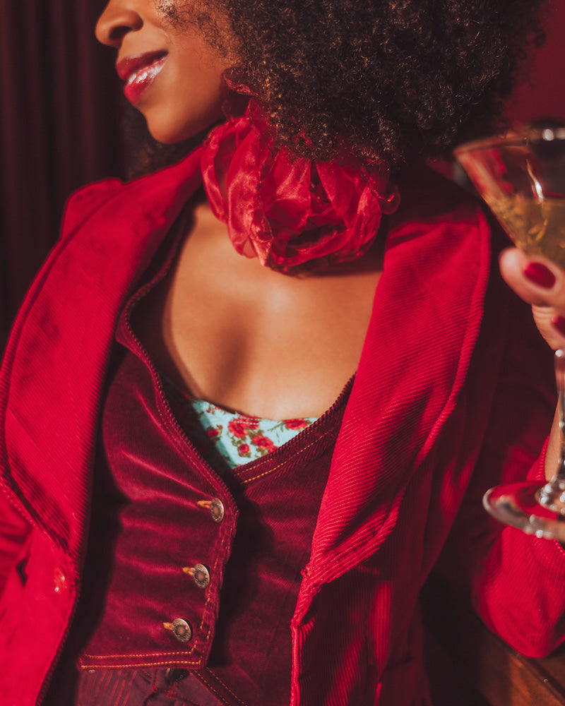 Woman in a red jacket holding a glass of champagne with a blurred background
