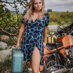 Woman in a blue dress standing next to a motorcycle in a natural setting wearing Soul Sister since 1969.