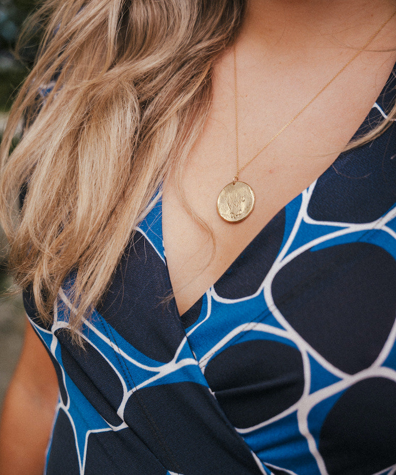 Close-up of a person wearing a blue patterned top with a gold necklace wearing Soul Sister since 1969..