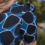 Person wearing a blue and black patterned top with blurred natural background wearing Soul Sister since 1969.