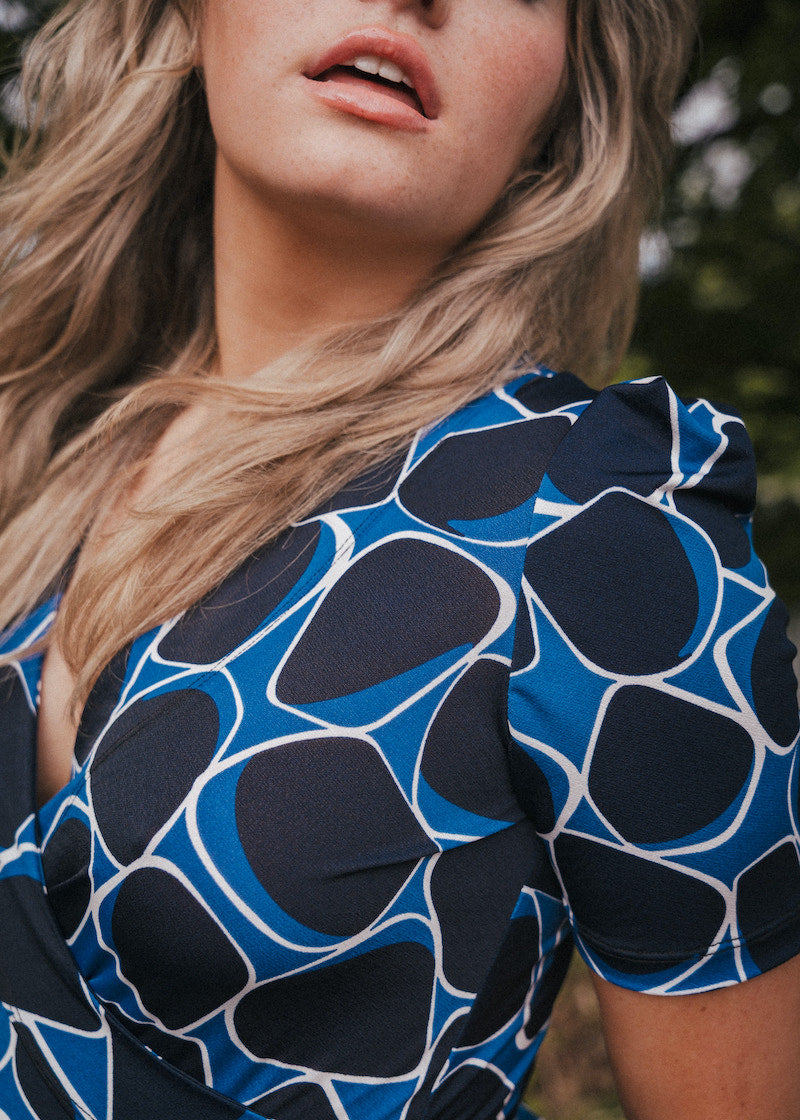 Close-up of a person wearing a blue and black patterned top with blurred background wearing Soul Sister since 1969.