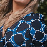 Close-up of a person wearing a blue and black patterned top with blurred background wearing Soul Sister since 1969.