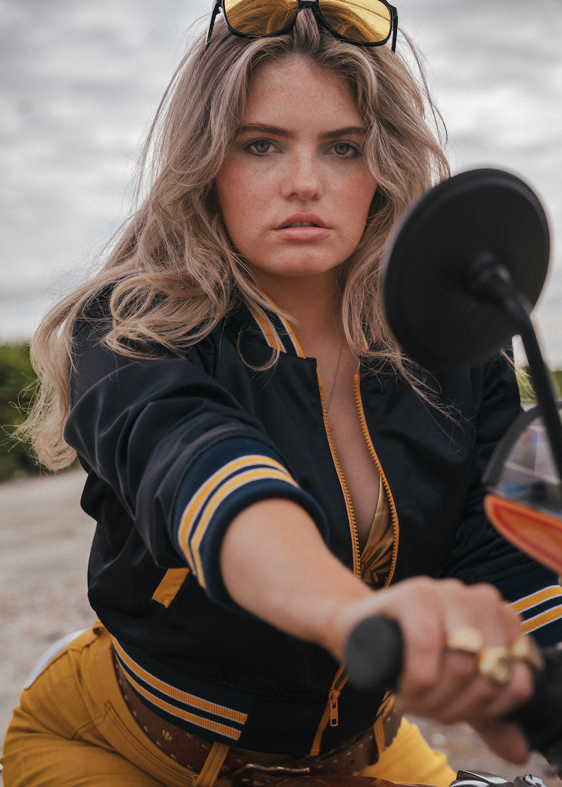 Woman on a motorcycle wearing a black and yellow jacket with sunglasses on her head Soul Sister since 1969 .