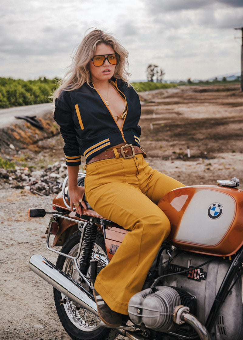 Woman sitting on a BMW motorcycle in an outdoor setting Soul Sister since 1969 