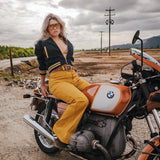 Woman sitting on a vintage BMW motorcycle in an open field with a cloudy sky Soul Sister since 1969  .