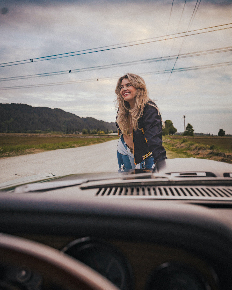 Woman standing on a road next to a car with a scenic background wearing Soul Sister since 1969