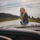 Woman standing on a road next to a car with a scenic background wearing Soul Sister since 1969